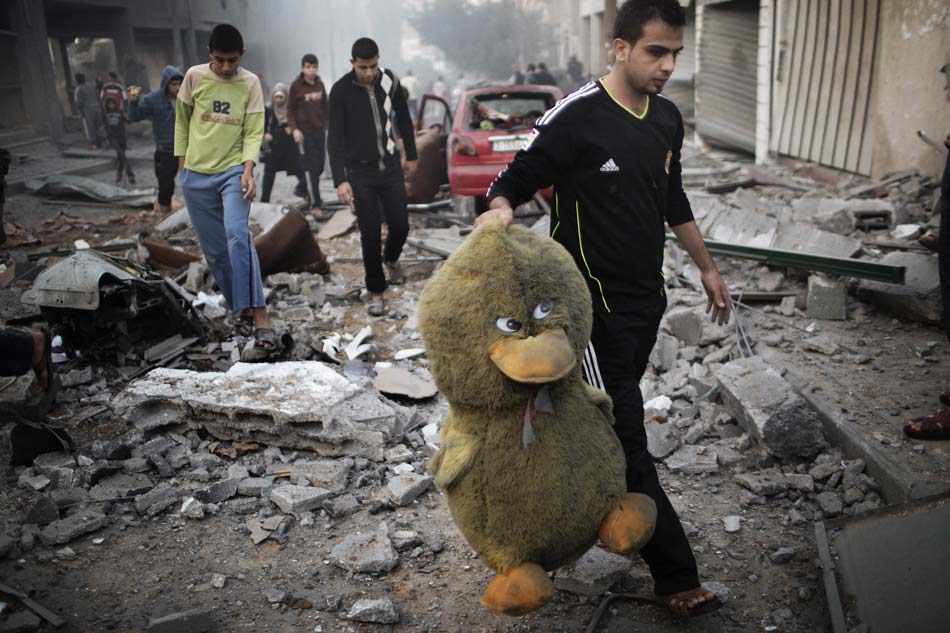A Palestinian picks up a stuffed toy from the ruins after the air raid in Gaza city on Nov. 19, 2012.(Xinhua/AFP)