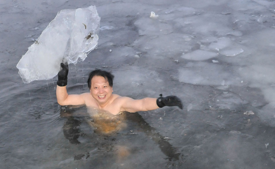A winter swimmer raises a piece of ice that’s floating on the lake in Changchun, capital city of northeast China’s Jilin province, Dec. 18, 2012. (Xinhua/Wu Haofei)