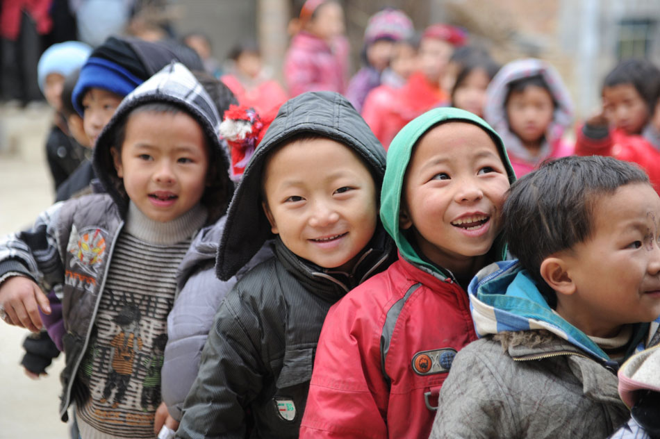Children from Gaida Primary School in Dongwang village in Luodian county of Guizhou province wait to get the new dresses on Dec. 19, 2012. (Xinhua/Taoliang)