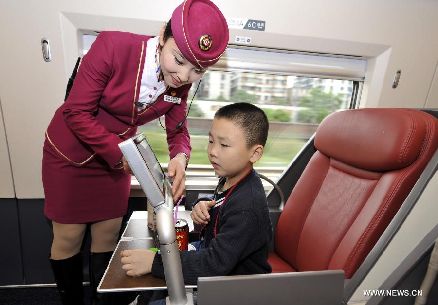 A stewardess adjusts a television set for a child in a business class carriage of G80 express train during a trip to Beijing, capital of China, Dec. 22, 2012. (Xinhua/Chen Yehua) 