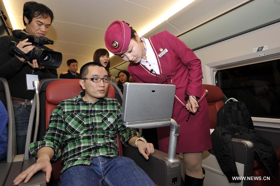 A stewardess adjusts a television set for a passenger in a business class carriage of G80 express train during a trip to Beijing, capital of China, Dec. 22, 2012.(Xinhua/Chen Yehua) 