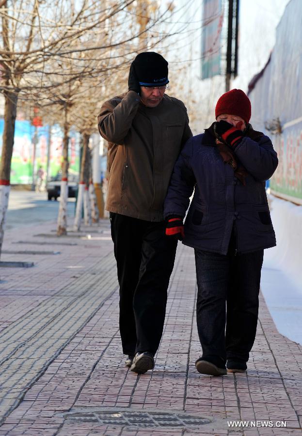 Two local residents walk in chill wind in Baoding, north China's Hebei Province, Dec. 23, 2012. The provincial meteorological observatory issued a blue alert on cold wave on Saturday. Most parts of Hebei suffered from a sharp decline of temperatures and strong wind. (Xinhua/Zhu Xudong) 