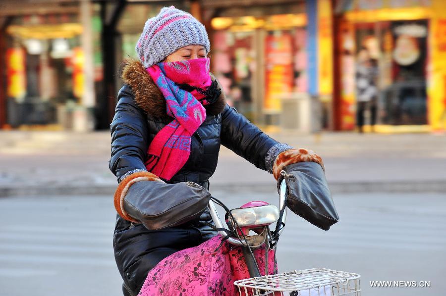 A local resident rides in chill wind in Baoding, north China's Hebei Province, Dec. 23, 2012. The provincial meteorological observatory issued a blue alert on cold wave on Saturday. Most parts of Hebei suffered from a sharp decline of temperatures and strong wind. (Xinhua/Zhu Xudong) 