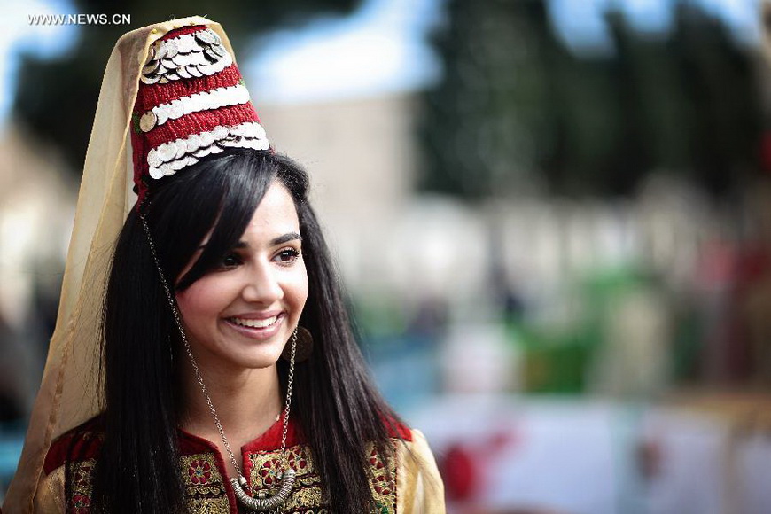 A girl wearing traditional clothes smiles at the Church of the Nativity, traditionally believed to be the birthplace of Jesus Christ, as she attends the Christmas celebrations in the West Bank biblical town of Bethlehem on Dec. 24, 2012. (Xinhua/Fadi Arouri)