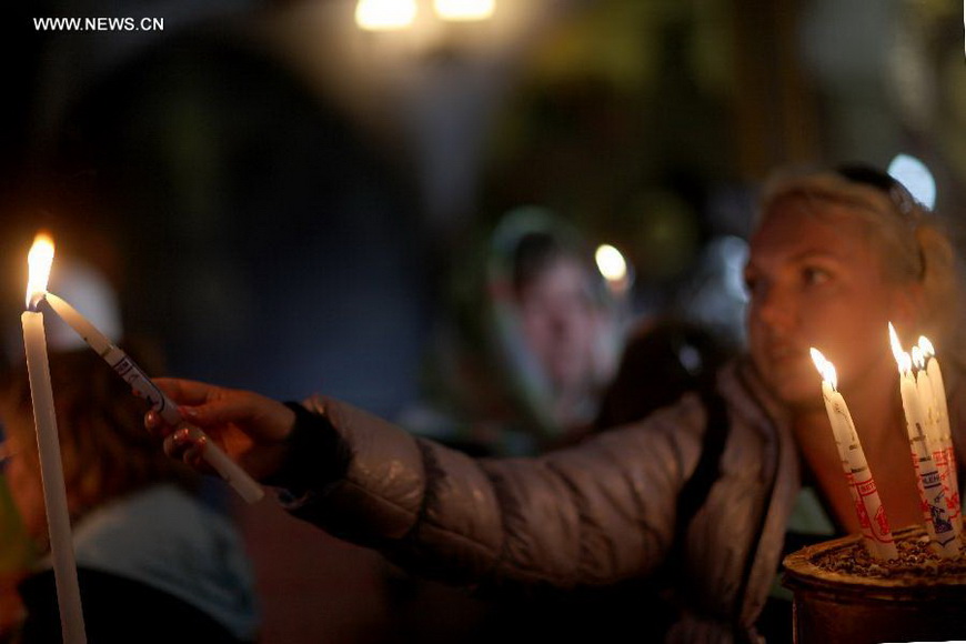 A worshiper lights a candle in the Church of the Nativity, traditionally believed to be the birthplace of Jesus Christ, as she attends the Christmas celebrations in the West Bank biblical town of Bethlehem on Dec. 24, 2012. (Xinhua/Fadi Arouri)