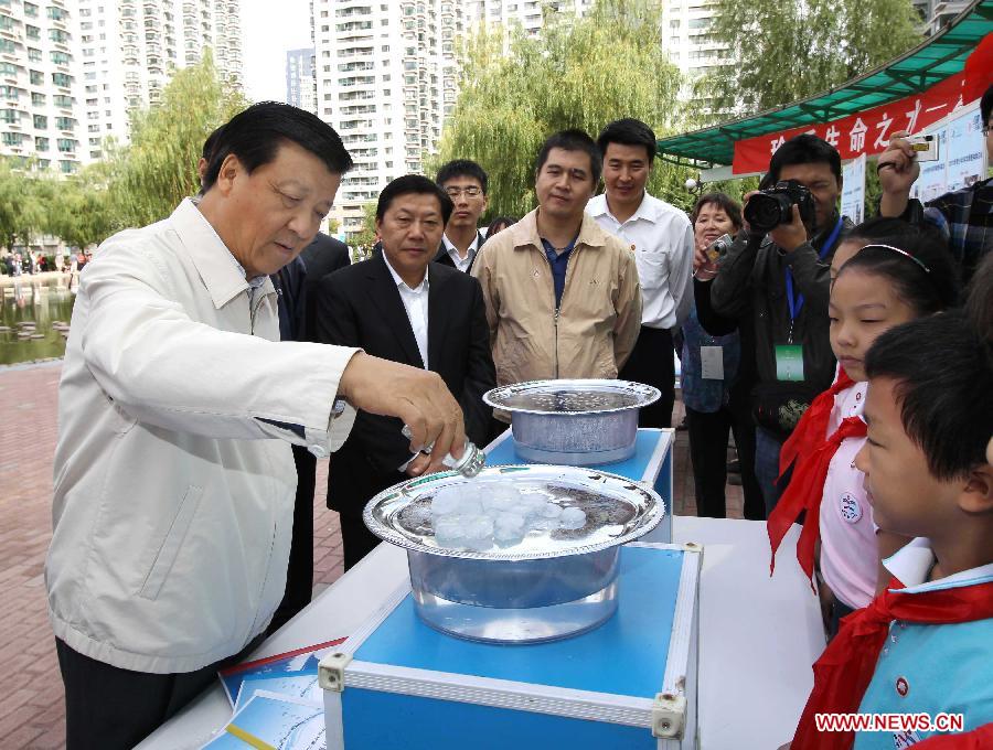In this file photo taken on Sept. 18, 2011, Liu Yunshan (L, front), then a member of the Political Bureau of the Communist Party of China (CPC) Central Committee, also a member of the Secretariat of the CPC Central Committee and head of the Publicity Department of the CPC Central Committee, does water-saving experiment with elementary school students during a National Science Day campaign at the Moliyuan community of Chaoyang District of Beijing, capital of China. (Xinhua/Liu Weibing)
