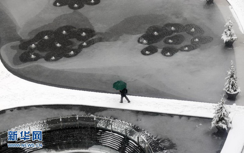 A man walks past a frozen fountain in the snow in Milan, Italy on Dec. 14, 2012. (Xinhua/AP photo)