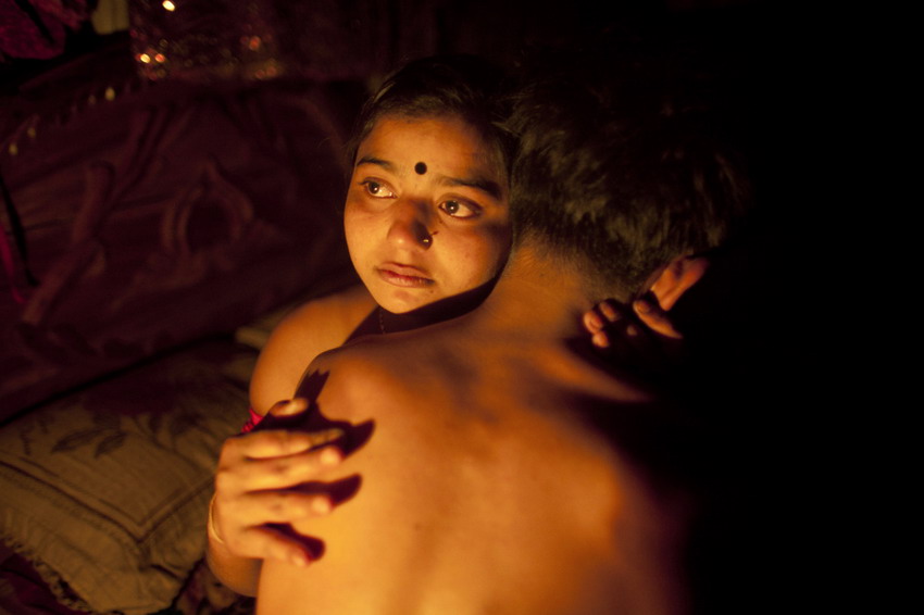 A seventeen-year-old prostitute hugs her “husband” in a small room in Tangail on March 4, 2012. (Reuters/ Andrew Biraj)