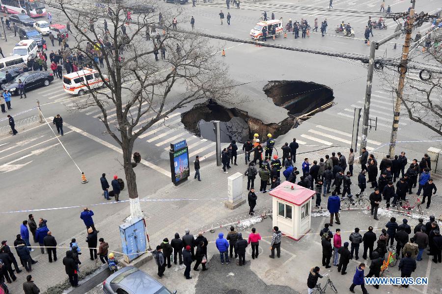 People gather around the collapsed section of a road intersection in Taiyuan, capital of north China' Shanxi province, Dec. 26, 2012. A hole, measuring around 5 meters deep and 15 meters wide, appeared after the road section collapsed. No casualties were reported. (Xinhua/Shi Xiaobo)