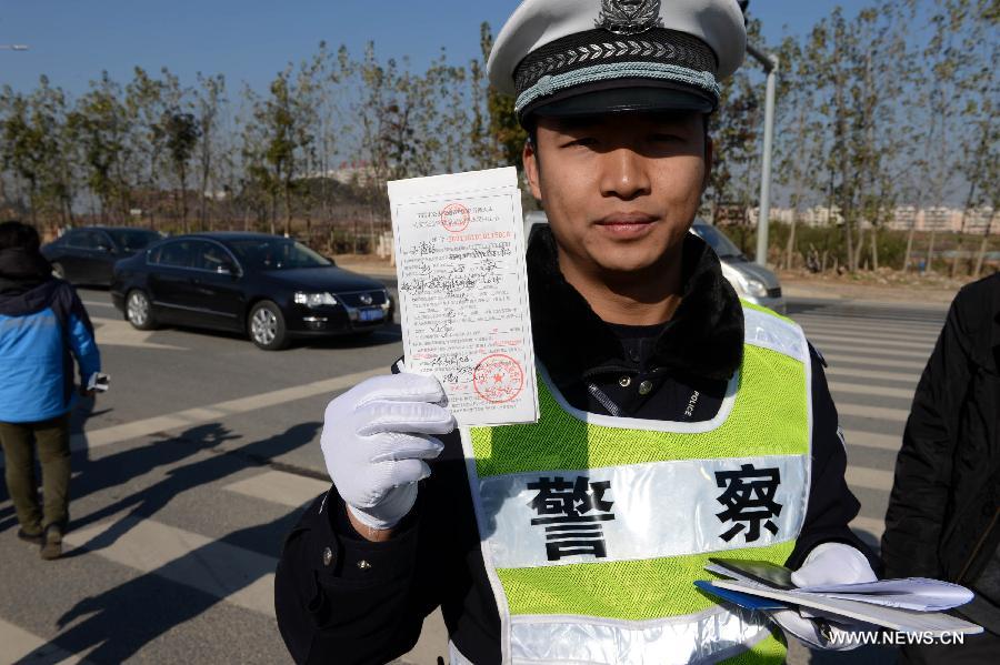 A policeman shows a ticket he just wrote in Nanchang City, capital of east China's Jiangxi Province, Jan. 1, 2013. The revised traffic regulation takes effect on Tuesday. According to the new rules, 52 different sorts of violations can result in deducting points for punishment, up from 38 under the previous regulation. (Xinhua/Song Zhenping)