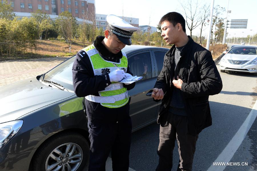 A policeman writes a ticket to a driver in Nanchang City, capital of east China's Jiangxi Province, Jan. 1, 2013. The revised traffic regulation takes effect on Tuesday. According the new rules, 52 different sorts of violations can result in deducting points for punishment, up from 38 under the previous regulation. (Xinhua/Song Zhenping) 