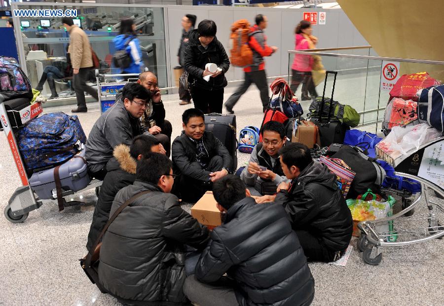 Passengers play cards together at Kunming Changshui International Airport in Kunming, capital of southwest China's Yunnan Province, Jan. 3, 2013. Affected by the dense fog, a total of 434 flights were cancelled and about 7,500 passengers were trapped in the airport until 9 p.m.Thursday.(Xinhua/Lin Yiguang) 