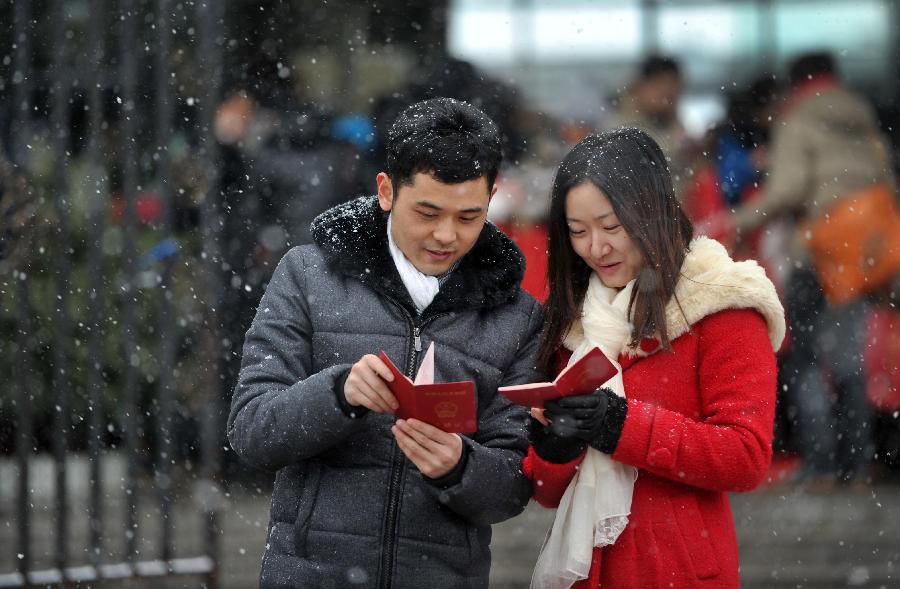 A couple look at their marriage certificates after registering in the marriage registration office in Furong District of Changsha, capital of central China's Hunan Province, Jan. 4, 2013. Quite a number of couples flocked to tie the knot on Jan. 4, 2013, or 2013/1/4, which sounds like "Love you forever" in Chinese. (Xinhua/Li Ga)