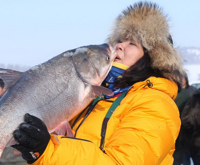 A female tourist is elated on buying the fish of her choice, at an ice-fishing event. (China Daily/Bai Shi)