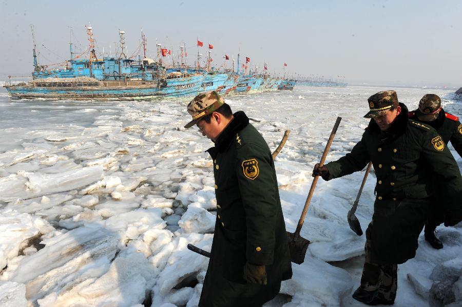 Policemen examine ice condition at Xidayang Fishing Wharf in Qingdao, east China's Shandong Province, Jan. 5, 2013. The ice conditions in the Bohai Sea and the Yellow Sea this January may be more serious than that in the past years, forecasted by North China Sea Marine Forecasting Center of State Oceanic Administration. (Xinhua/Li Ziheng)