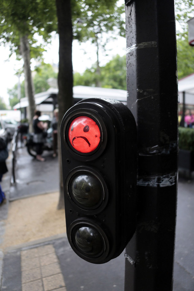 A picture taken on June 26, 2012 shows a graffiti depicting a smiley face on a red traffic light in Paris. (ImagineChina/ Jacques Demarthon)