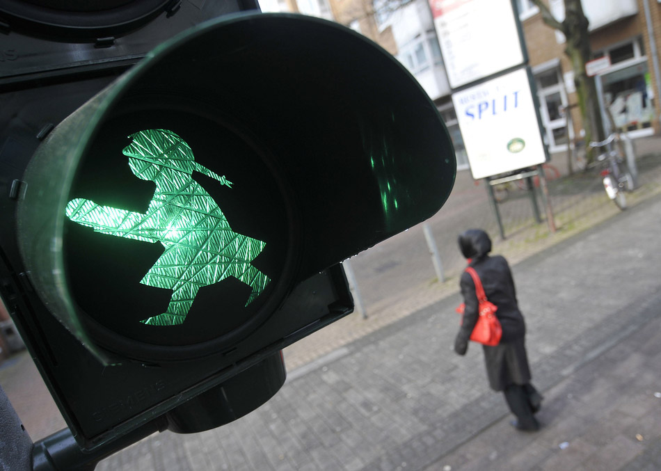 A traffic light bearing an “Ampelmaedchen” (little traffic light girl) signals green at a street in the western German city of Cologne on March 13, 2009. (ImagineChina/ Henning Kaiser)