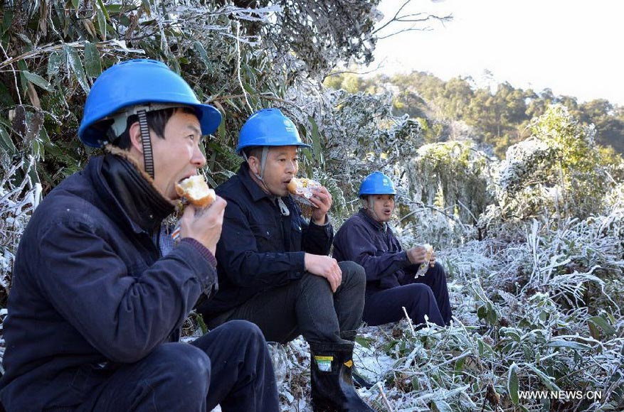 Staff members of local power supply bureau have a meal while checking power transmission lines in Nanping City, southeast China's Fujian Province, Jan. 5, 2013. Nanping Power Supply Bureau took measures to repair the mal-functioned power transmission lines affected by the freezing rain and snow weather here in recent days. (Xinhua/Chen Shuzhong) 