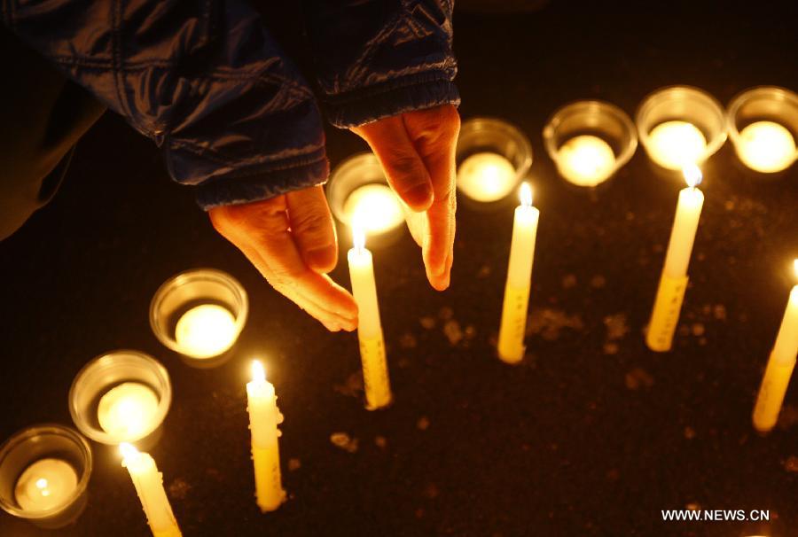 A citizen stretches his hands to keep out the wind from a candle during a memorial service for the three firefighters who died while putting out fire in a factory blaze, at the Wushan Square in Hangzhou, capital of east China's Zhejiang Province, Jan. 7, 2013. Local citizens gathered here on Monday evening to mourn the three firefighters who sacrificed their lives while putting out a fire in Hangzhou's Xiaoshan District, six days after the fire broke out. The three firefighters, Yin Jinliang, Chen Wei and Yin Zhihui, were ratified as martyrs and awarded gold medals for their dedication to the national defence. They were also personally awarded the top-grade merit citation. (Xinhua/Cui Xinyu) 