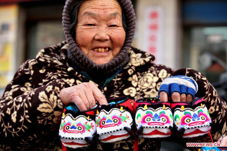 An old woman shows her handmade tiger-head shoes in downtown Bozhou City, east China's Anhui Province, Jan. 7, 2013. Tiger-head shoes, a kind of traditional Chinese shoes made of colourful cotton fabric and thread, are popular for local people who hope their children grow as robust and healthy as tigers in the new year. (Xinhua/Liu Qinli) 