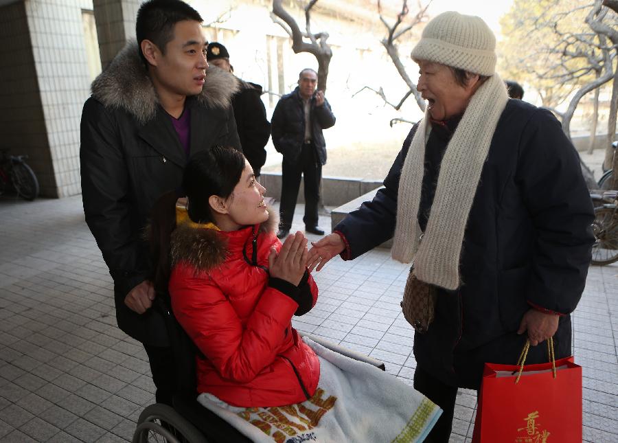 Zhang Lili, a teacher who lost her legs while saving two students from an onrushing bus, receives praise from a retired teacher at the China Rehabilitation Research Center in Beijing, capital of China, Jan. 7, 2013. Zhang, who successfully pushed the students out of the harm's way but unable to avoid the bus herself and lost her legs in the accident, has been receiving rehabilitative treatment here for over 4 months. Zhang makes great efforts now in order to be able to walk again. (Xinhua/Jin Liwang) 