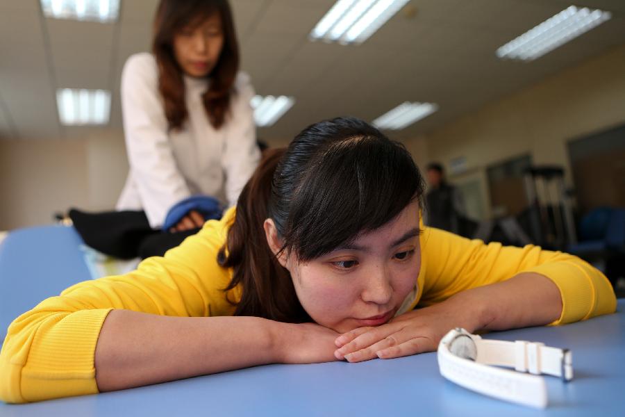 Zhang Lili, a teacher who lost her legs while saving two students from an onrushing bus, does rehabilitative training under the help of a doctor at the China Rehabilitation Research Center in Beijing, capital of China, Jan. 7, 2013. Zhang, who successfully pushed the students out of the harm's way but unable to avoid the bus herself and lost her legs in the accident, has been receiving rehabilitative treatment here for over 4 months. Zhang makes great efforts now in order to be able to walk again. (Xinhua/Jin Liwang) 