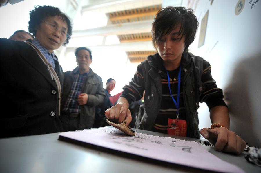 A staff member of the Hainan Provincial Museum makes rubbgings at a tour exhibition of Venerable Master Hsing Yun's One-Stroke Calligraphy held at the museum in Haikou, capital of south China's Hainan Province, Jan. 8, 2013. A total of 55 calligraphy works by master Hsing Yun were on display at the exhibition that will last until Jan. 20. (Xinhua/Guo Cheng)  