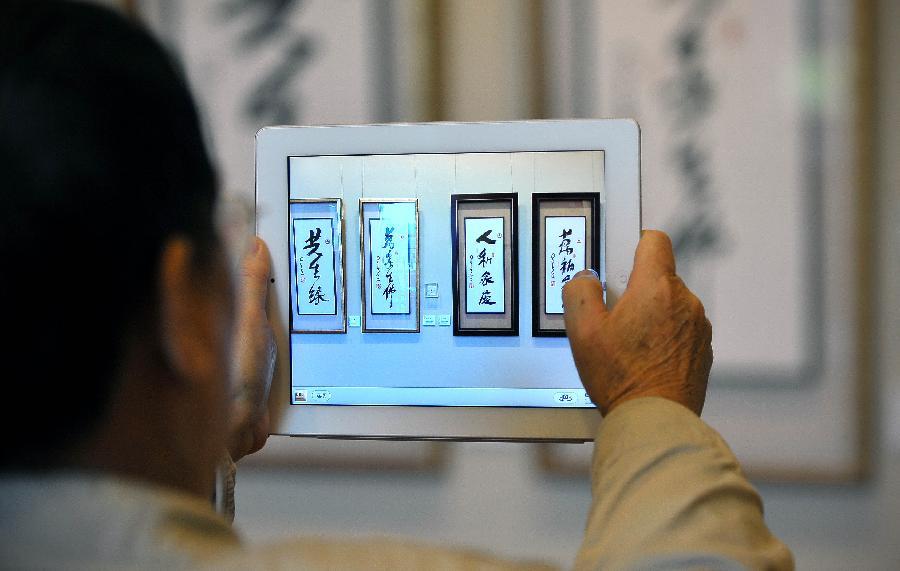 A visitor takes photos at a tour exhibition of Venerable Master Hsing Yun's One-Stroke Calligraphy held at the Hainan Provincial Museum in Haikou, capital of south China's Hainan Province, Jan. 8, 2013. A total of 55 calligraphy works by master Hsing Yun were on display at the exhibition that will last until Jan. 20. (Xinhua/Guo Cheng) 
