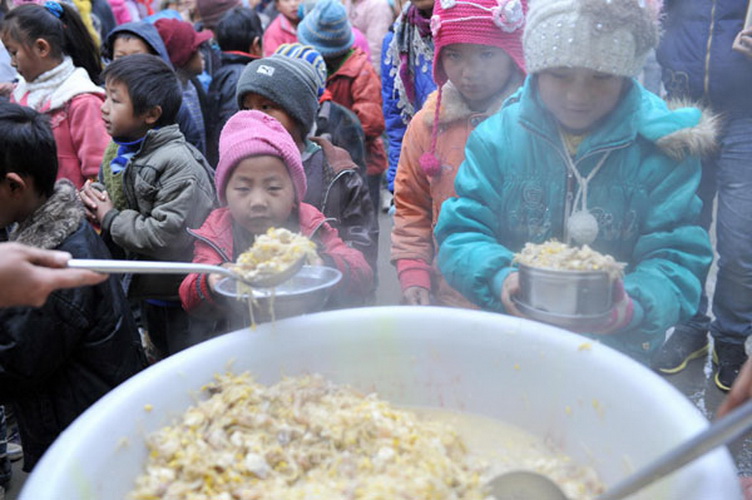 Students get free lunch at Longdong Primary School in Longlin county, Guangxi Zhuang autonomous region, Jan 8, 2013. Free lunch covers 1.16 million rural students in 40 counties and regions in Guangxi. Since autumn 2011, with the release of "Guidance on Nutritional Improvement Plan for Rural Students" by the State Council, the free lunch program sponsored by city and county governments has become nationally funded. (Photo/Xinhua)