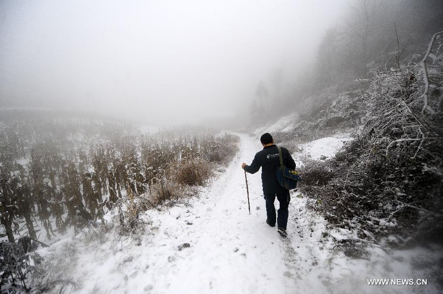 Postman Zhang Meichong walks on a snow-covered road in fog to send letters at a mountainous village in Enshi, central China's Hubei Province, Dec. 23, 2012. Equipped with a stick and two bags, Zhang Meichong, a village postman, has been working in the mountainous area for 15 years and traveled a distance about 180,000 kilometers these years. (Xinhua/Hao Tongqian)  
