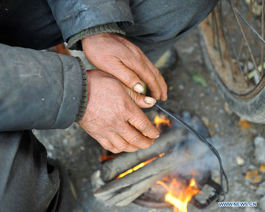 A man warms his hands by a fire at a street market of Quanzhou County in Guilin, southwest China's Guangxi Zhuang Autonomous Region on Jan. 9, 2013. The meteorological observatory in Guangxi issued a yellow alert for frost on Wednesday afternoon. (Xinhua/Lu Bo'an)