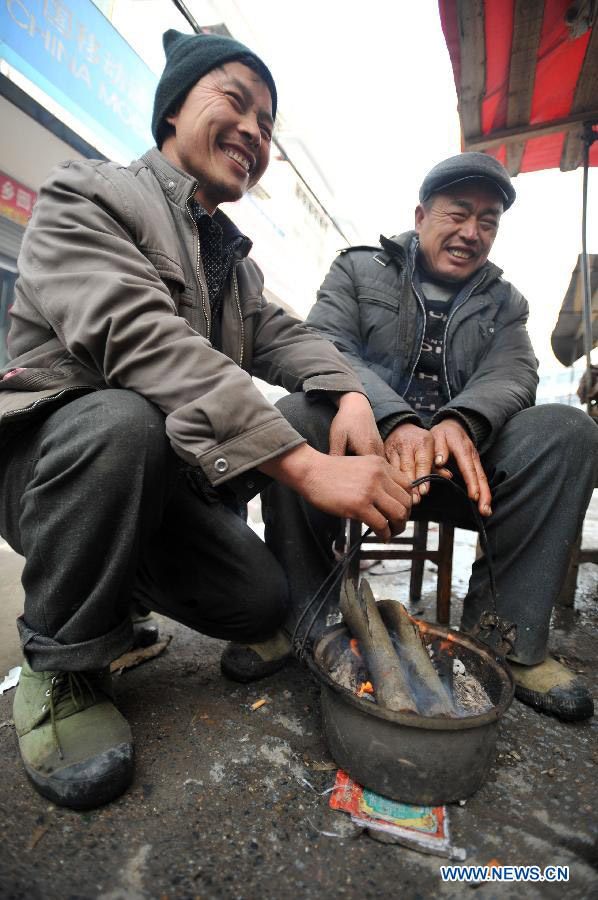 People warm themselves by a fire at a street market of Quanzhou County in Guilin, southwest China's Guangxi Zhuang Autonomous Region on Jan. 9, 2013. The meteorological observatory in Guangxi issued a yellow alert for frost on Wednesday afternoon. (Xinhua/Lu Bo'an)