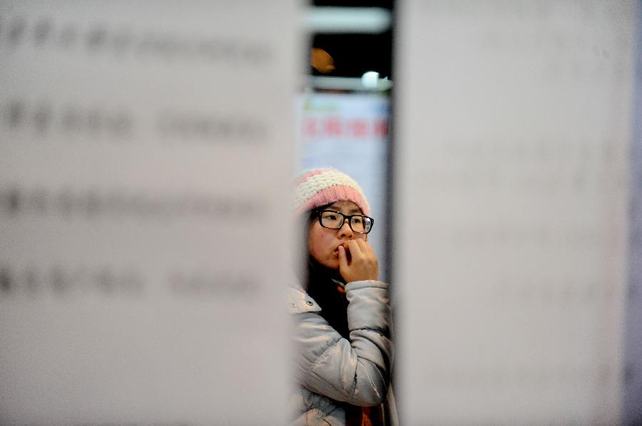 A job seeker views the information board at a job fair in Shenyang, capital of northeast China's Liaoning Province, Jan. 12, 2013. A total of 168 companies provided some 3,000 job vacancies at the job fair. (Xinhua) 