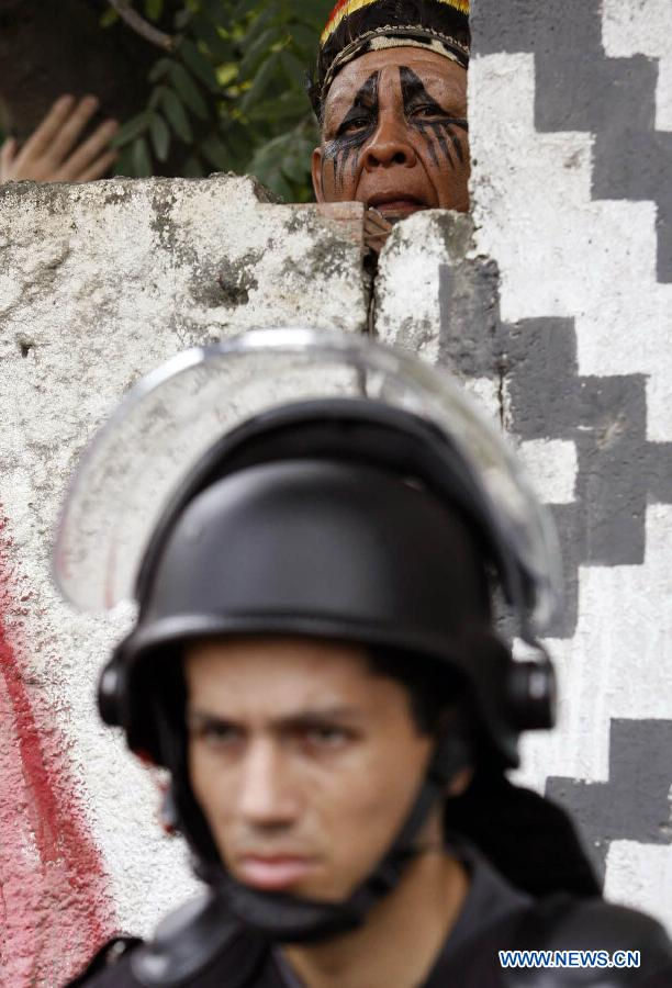 An Indian man looks at Special Police Operations Battalion (BOPE) members during a BOPE operation to evict a group of Indians camping in the Indian Museum, in Rio de Janeiro, Brazil, on Jan. 12, 2013. On Saturday morning, BOPE's members arrived at the museum that will be demolished to evict the Indians. The demolition was carried out with the aim of building modernization works to the adjoining Maracana Stadium, as part of the preparations for Brazil's World Cup 2014. (Xinhua/Luiz Roberto Lima/AGENCIA ESTADO)