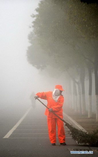 A sanitation worker sweeps a street amid heavy fog in Nanchang, capital of east China's Jiangxi Province, Jan. 14, 2013. Nanchang's air has been heavily polluted for five days in a row, according to local meteorological authorities. (Xinhua/Zhou Ke)