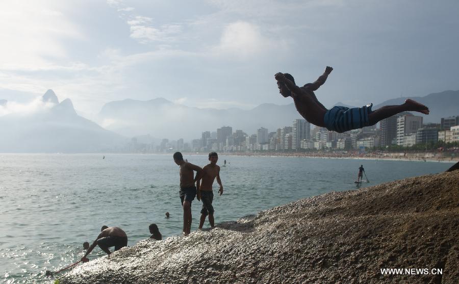 A boy jumps into the sea from a rock in Arpoador in Rio de Janeiro, Brazil, Jan. 13, 2013.(Xinhua/Weng Xinyang)