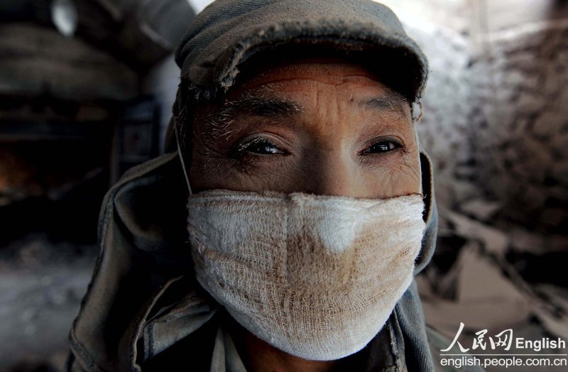 A worker’s face is covered by dust in a lime processing factory on Dec. 5, 2012. (Photo/People's Daily Online)