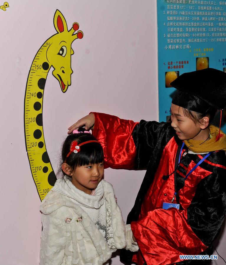 A working staff helps a girl measure her height at the science experience hall for youths in the Heilongjiang Museum in Harbin, capital of northeast China's Heilongjiang Province, Jan. 15, 2013. As winter holiday begins in Harbin, children can visit the hall for free and take part in scientific lectures held by the museum. (Xinhua/Wang Song)