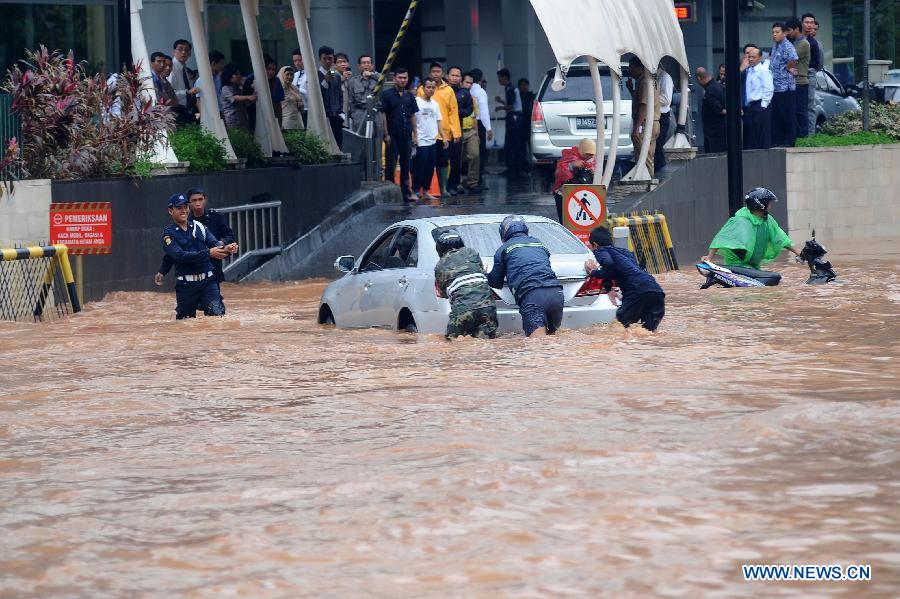 People push a car in flood waters in Jakarta, Indonesia, Jan. 17, 2013. The Indonesian capital city of Jakarta was paralyzed by flood on Thursday following a massive downpour since Wednesday night, with its main roads inundated, public transport disrupted and operation of government offices and private sector coming to a standstill. (Xinhua/Veri Sanovri)