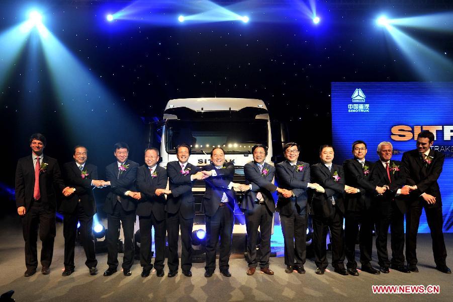 Guests pose for photos in front of the first SITRAK duty truck during the off assembly line ceremony at the China National Heavy Duty Truck Group (CNHTC) Jinan Commercial Vehicle Co. Ltd, in Jinan, capital of east China's Shandong Province, Jan. 17, 2013. As advanced heavy duty truck produced by CNHTC in cooperation with MAN Truck & Bus AG from Germany (MAN), the SITRAK duty truck was off assembly line on Thursday. (Xinhua/Xu Suhui) 