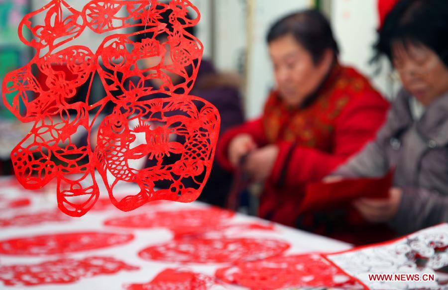 People cut the Chinese character "Fu" , or "happiness", in Fuyuyuan Committee of Quanhe Street in Huairou District, Beijing, capital of China, Jan. 17, 2013. The committee will send the paper-cuts of "Fu" to families as a gift for the coming Spring Festiva. (Xinhua/Bu Xiangdong) 