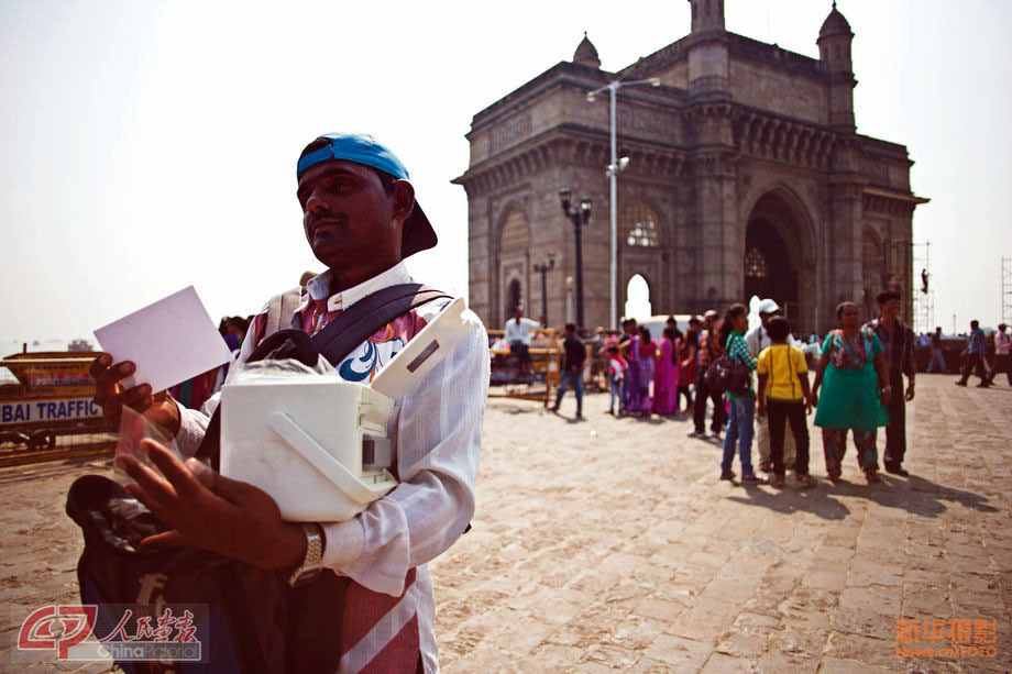 A photographer attracts business in the square near Gateway of India. He carries a convenient color printer. (Chinapictorial/ Duan Wei)