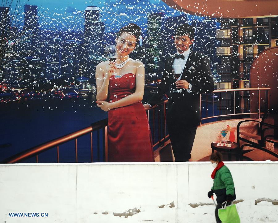 An old woman walks past a billboard with snow on it in Taiyuan City, capital of north China's Shanxi Province, Jan. 21, 2013. Snowfall hit Taiyuan at the weekend. (Xinhua/Yan Yan)