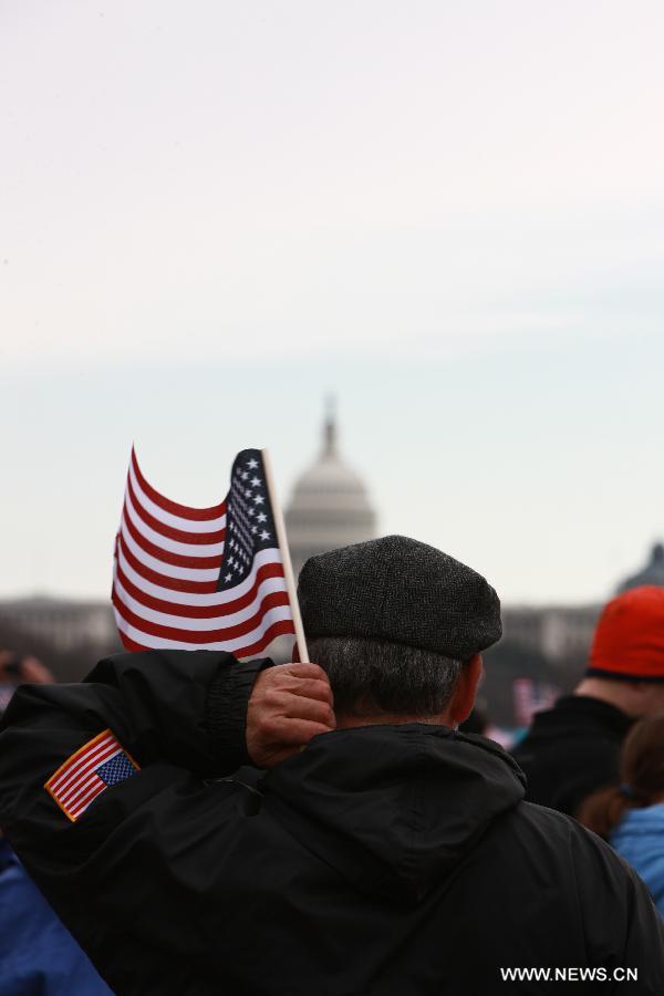 A spectator holding a U.S. national flag watches the presidential inauguration ceremony on the West Front of the U.S. Capitol in Washington D.C., the United States, on Jan. 21, 2013. (Xinhua/Zhai Xi) 