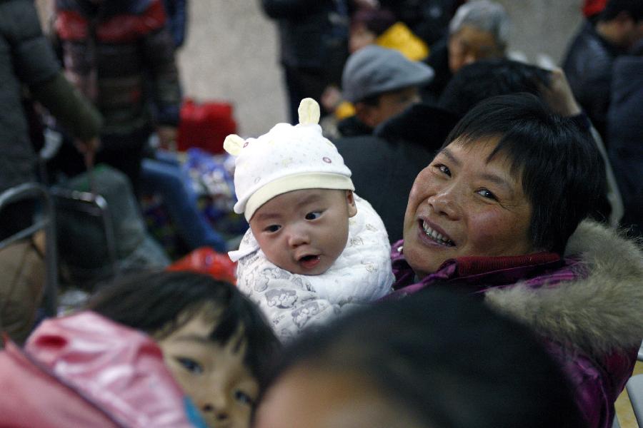 A woman holds a baby to wait for their train home at Hangzhou train station in Hangzhou, capital of east China's Zhejiang Province, Jan. 22, 2013. Many migrant workers and their children have started to return home in order to avoid the Spring Festival travel peak that begins on Jan. 26 and will last for about 40 days. The Spring Festival, the most important occasion for a family reunion for the Chinese people, falls on the first day of the first month of the traditional Chinese lunar calendar, or Feb. 10 this year. (Xinhua/Cui Xinyu)