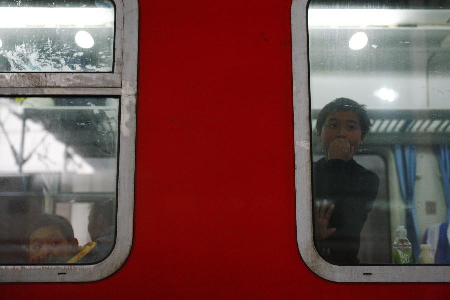 Two children look out of a window on a train which is about to pull out in Hangzhou, capital of east China's Zhejiang Province, Jan. 22, 2013. Many migrant workers and their children have started to return home in order to avoid the Spring Festival travel peak that begins on Jan. 26 and will last for about 40 days. The Spring Festival, the most important occasion for a family reunion for the Chinese people, falls on the first day of the first month of the traditional Chinese lunar calendar, or Feb. 10 this year. (Xinhua/Cui Xinyu)