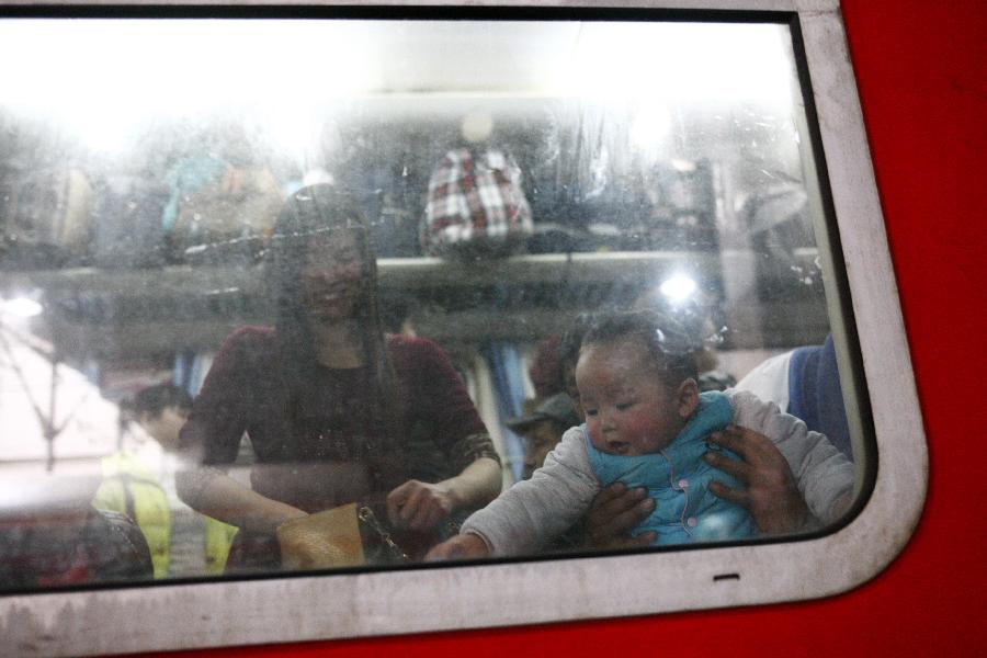 A child plays by the side of a window on a train which is about to pull out in Hangzhou, capital of east China's Zhejiang Province, Jan. 22, 2013. Many migrant workers and their children have started to return home in order to avoid the Spring Festival travel peak that begins on Jan. 26 and will last for about 40 days. The Spring Festival, the most important occasion for a family reunion for the Chinese people, falls on the first day of the first month of the traditional Chinese lunar calendar, or Feb. 10 this year. (Xinhua/Cui Xinyu)