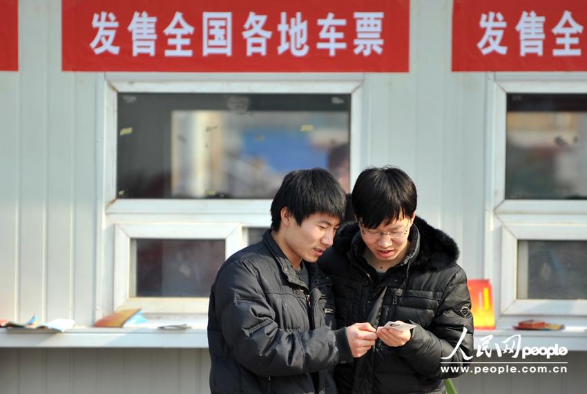 Homecoming people buy train ticket with anxiety outside a temporary ticket booth set at Beijing Railway Station, Jan. 22. The Spring Festival travel peak is going to begin on Jan. 26 and will last about 40 days. Railway passenger trips are expected to hit 225 million during the upcoming travel peak. (People’s Daily Online/Weng Qiyu)