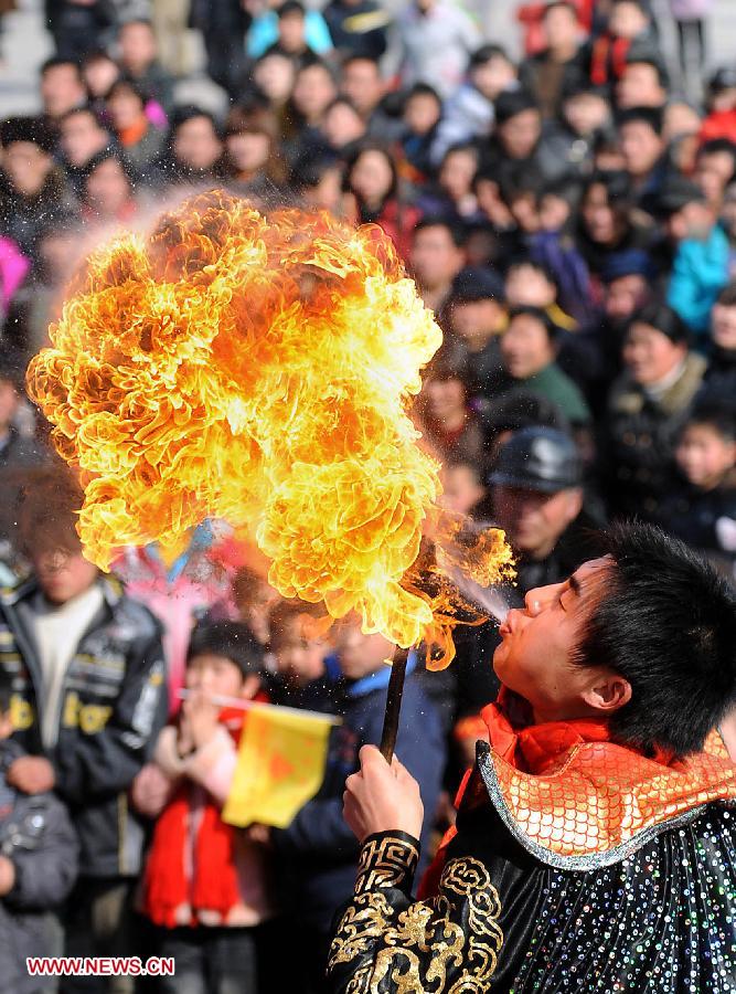 File photo taken on Feb. 20, 2010 shows a folk artisan performs his unique skill of spitting fire from the mouth at a temple fair in Shangqiu City, central China's Henan Province. Temple fair in central China area is an important social activity for local people. The ancient temple fairs in central China were ceremonious sacrificial rituals. As time goes by, the focus of temple fair activities has shifted from "gods" to "people". The modern temple fair in central China is a platform of displaying folk culture as well as a channel for commodity circulation. According to statistics from the provincial cultural sector, there are about 35,000 temple fairs each year in Henan. (Xinhua/Wang Song)