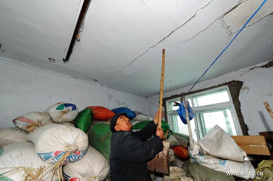 A villager points to the ceiling destroyed by an earthquake in Haozitun Village of Liutiaozhai Township in county-level city of Dengta, northeast China's Liaoning Province, Jan. 23, 2013. A 5.1-magnitude earthquake jolted the border region of Dengta and Shenyang cities in Liaoning at 12:18 p.m. (0418 GTM) on Wednesday. The epicenter, with a depth of about 7 kilometers, was located near Dengta and the Sujiatun District of Shenyang, capital of Liaoning Province, at 41.5 degrees north latitude and 123.2 degrees east longitude. Liu Wenlong, mayor of Dengta, said the city government has not received any reports about casualties or house collapse. No casualties or house collapses have been reported yet. (Xinhua/Yang Qing)